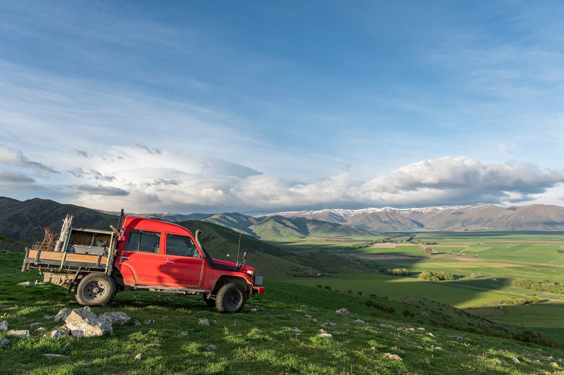 A station truck parked on the tops, looking out over the green valley to the snow-capped ranges